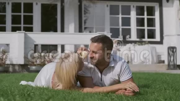 已婚夫妇躺在草地上接吻孩子们在他们附近玩耍和跑步视频的预览图