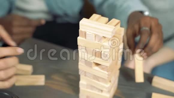 木块塔在桌子上玩方块移除游戏的朋友的近距离手视频的预览图