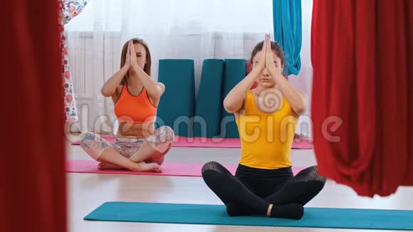 瑜伽两个女人坐在垫子上做呼吸练习明亮工作室视频的预览图
