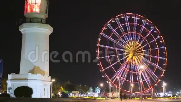 灯塔附近的摩天轮在巴统堤岸的夜晚旋转视频的预览图