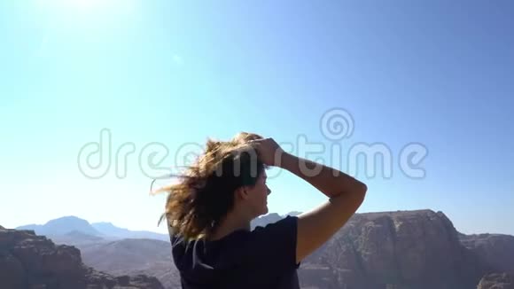 红发独立女站在山的边缘欣赏美丽的景色视频的预览图