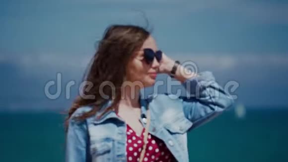 阳光明媚的一天戴着墨镜的美女头发笔直地走在地中海的海滨视频的预览图