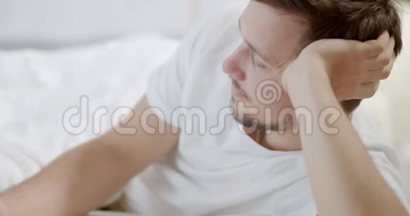穿白色衬衫的年轻人躺在白色床上放松4K关门视频的预览图