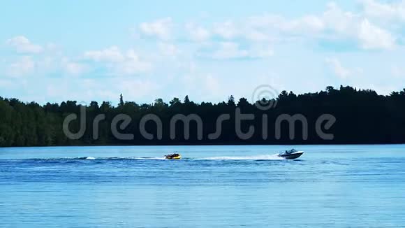 在美丽的明尼苏达湖上划船游乐速度摩托艇在波浪上拉一根娱乐管骑手摔倒了视频的预览图