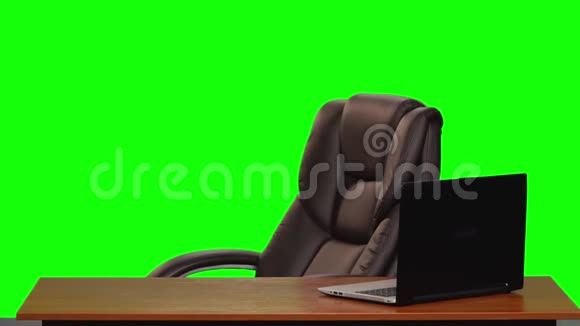 皮革商务椅在一张带有笔记本电脑的桌子附近旋转绿色屏幕慢动作视频的预览图
