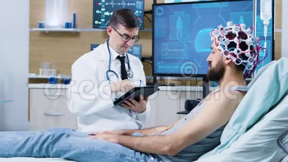脑研究医生住在病人床旁边打平板电脑视频的预览图
