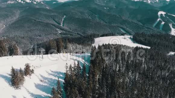 滑雪场上有滑雪者和滑雪升降机的空中滑雪斜坡雪山森林视频的预览图