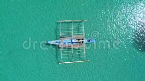 在阳光明媚的日子里用清澈绿松石的海水锚定在海湾中的菲律宾传统船邦加航空无人机观景图视频的预览图