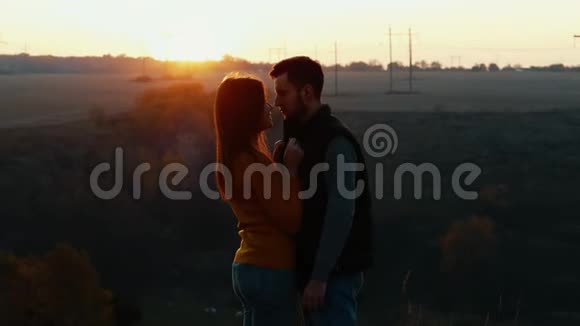 在日落亲吻前可爱的一对情侣看着对方眼睛视频的预览图