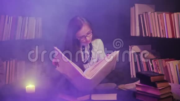 一个女孩在图书馆里打开一本童话书彩色的烟雾缭绕蜡烛在附近点燃视频的预览图