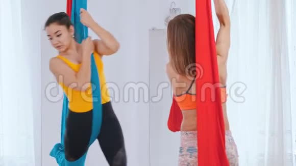 两个女人在工作室接受空中瑜伽训练吊在吊床上视频的预览图
