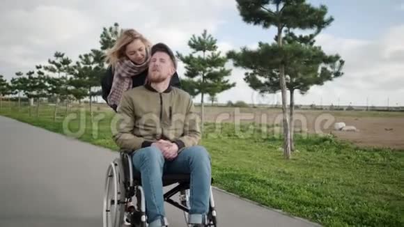 金发女人和她的残疾男友在户外滚动轮椅视频的预览图