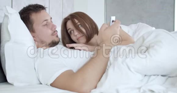 女人正紧紧地依偎着她的男朋友她的电话里有一张脸4K视频的预览图