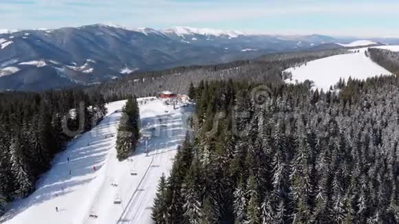 滑雪场上有滑雪者和滑雪升降机的空中滑雪斜坡雪山森林视频的预览图