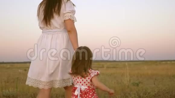 快乐的童年概念孩子牵着妈妈手一个幸福的家庭在晚上走出城镇妈妈走在田野上视频的预览图