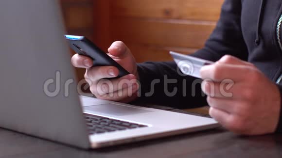 穿着黑色连帽衫的商人用信用卡和智能手机进行网上支付网上购物视频的预览图
