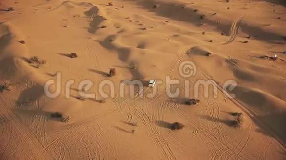 沙漠沙丘上一辆白色大轿车的空中追踪拍摄视频的预览图
