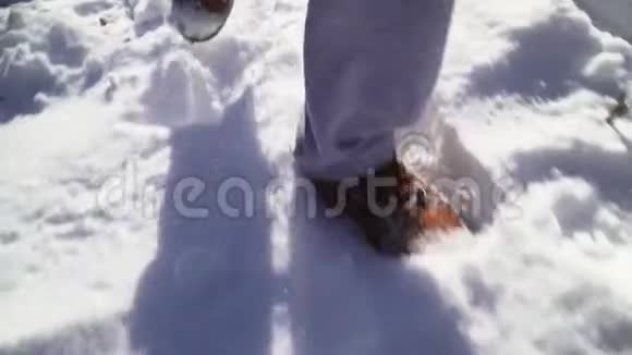 特写镜头男人穿着雪棕色的冬靴和灰色的运动裤雪冬天的气氛视频的预览图