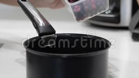 女性手把浆果从容器中倒入黑色炖锅视频的预览图