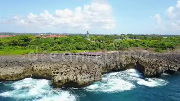 巴厘岛一个阳光明媚的夏日里一个岩石海岸的空中摄影海浪从海洋中冲破视频的预览图
