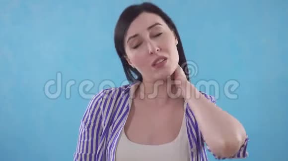 年轻女子脖子上疼痛站在蓝色背景上的时候戴上保护项圈视频的预览图