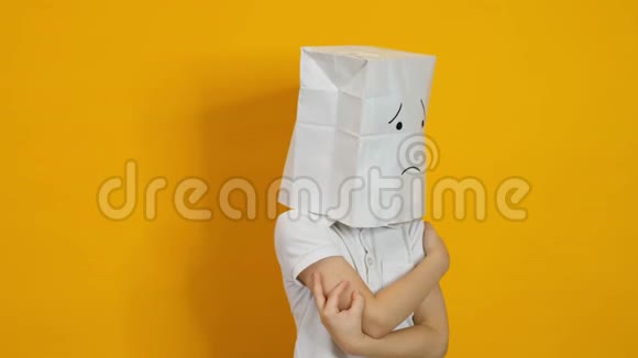 头上戴着袋子的小男孩黄色背景上悲伤的不受欢迎的脸视频的预览图