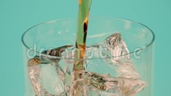 将棕色软饮料倒入一个充满冰块的玻璃杯中以青色为背景慢镜头对准红色视频的预览图