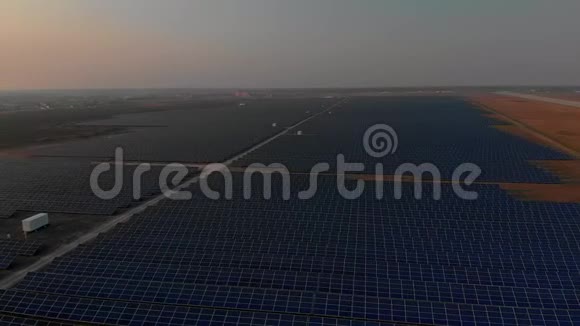 在明亮的夕阳下空中无人机在太阳能农场观看大型太阳能电池板太阳能电池发电厂录像4K视频的预览图