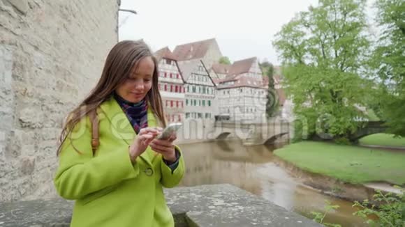 年轻女性使用智能手机附近的堡垒墙和桑斯坦布拉克桥或斯坦纳斯特格半定时视频的预览图