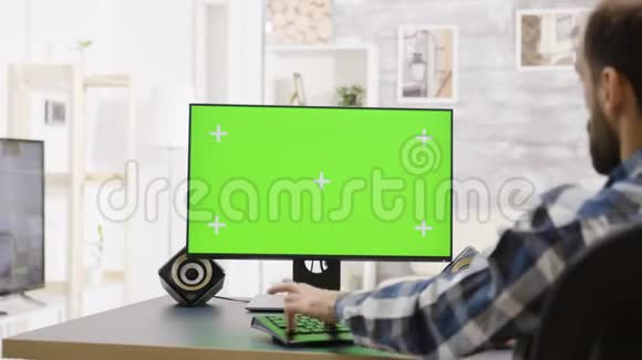 男子工作在绿色屏幕PC显示器肩膀以上射击视频的预览图
