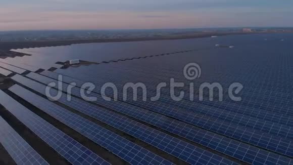 空中无人机在日落时进入太阳能农场的大型太阳能电池板太阳能电池发电厂录像4K视频的预览图
