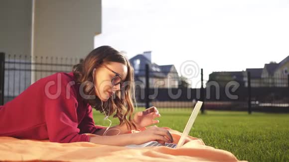 戴着眼镜的年轻女孩输入她的信用卡号码一台笔记本电脑后院视频的预览图