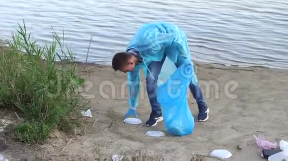 英俊的年轻志愿者带着团队在河岸上收集垃圾视频的预览图