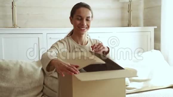 兴奋的年轻女子打开纸板箱拿邮包视频的预览图