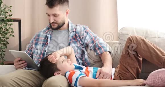 男孩在父亲腿上放松听电子书故事视频的预览图