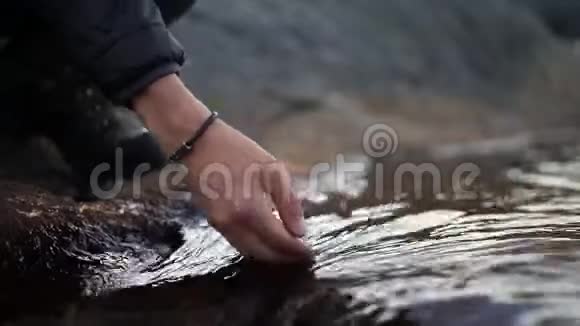 双手特写一个徒步旅行者把手伸进一条冰冷的河里特写镜头视频的预览图