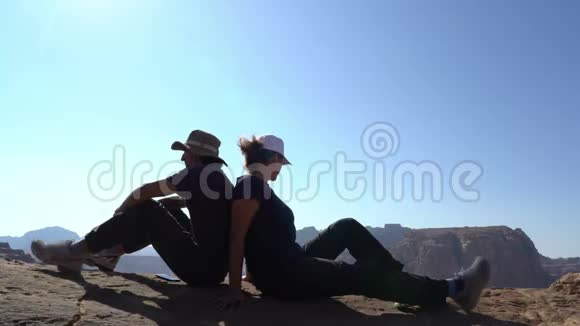 恋爱中的情侣关系坐在山边的男女欣赏风景家庭团队视频的预览图