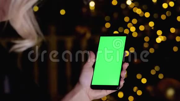 女性手拿着带有彩色垂直绿色屏幕模型的手机视频的预览图