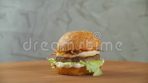一个大的美味汉堡里面有肉馅饼洋葱蔬菜融化奶酪生菜视频的预览图