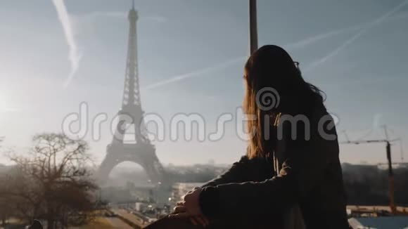 巴黎埃菲尔铁塔度假时的全景坐在史诗般夕阳下的观景围栏上的年轻旅游妇女快乐视频的预览图