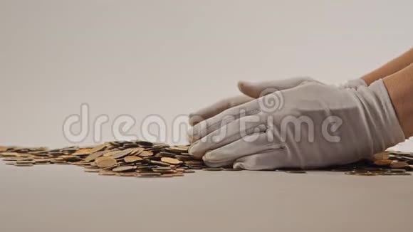 白手套的手舀起一堆金币他们整理和分散金钱在白色背景上加兰视频的预览图