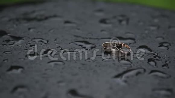 美丽的金色结婚戒指在潮湿的表面与水滴视频的预览图