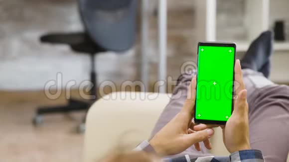 男子手中拿着绿色屏幕手机的视差镜头视频的预览图