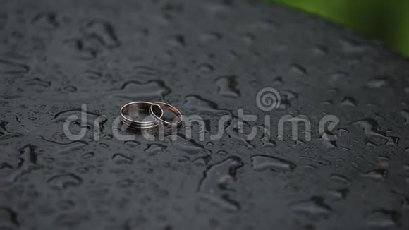 美丽的金色结婚戒指在潮湿的表面与水滴视频的预览图