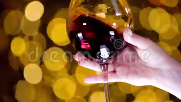 女性手拿着一杯红酒在金色高光的背景下移动视频的预览图