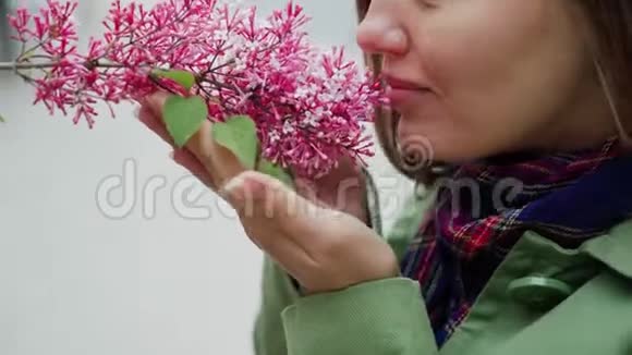 美丽的女人享受着粉红色丁香的味道可爱的模特和鲜花芳香疗法和春季视频的预览图