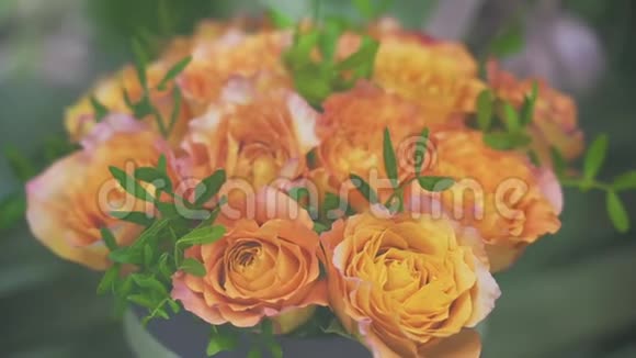 在花店橱窗里特写一束新鲜的橙色玫瑰和绿色植物视频的预览图