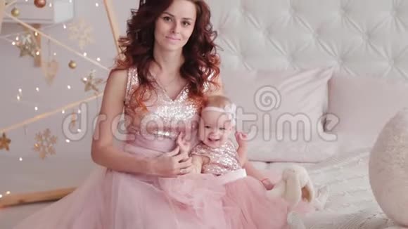 美丽的母亲和一个一岁的女儿穿着漂亮的裙子和新年装饰2020年新年视频的预览图