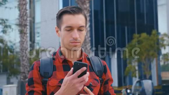 特写年轻人在城市里使用电话游客穿着红色衬衫在玻璃背景上使用手机视频的预览图
