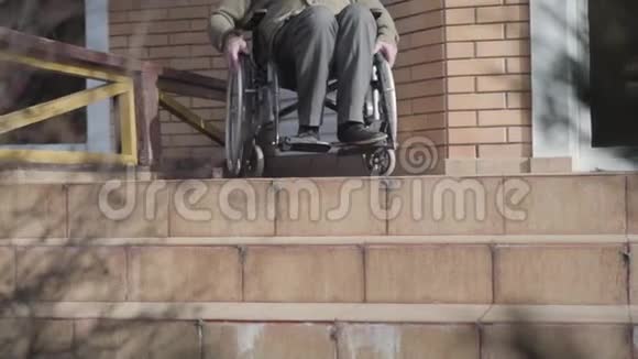无法辨认的老白种人坐在轮椅上滚到楼梯上停下来残疾人无机会视频的预览图